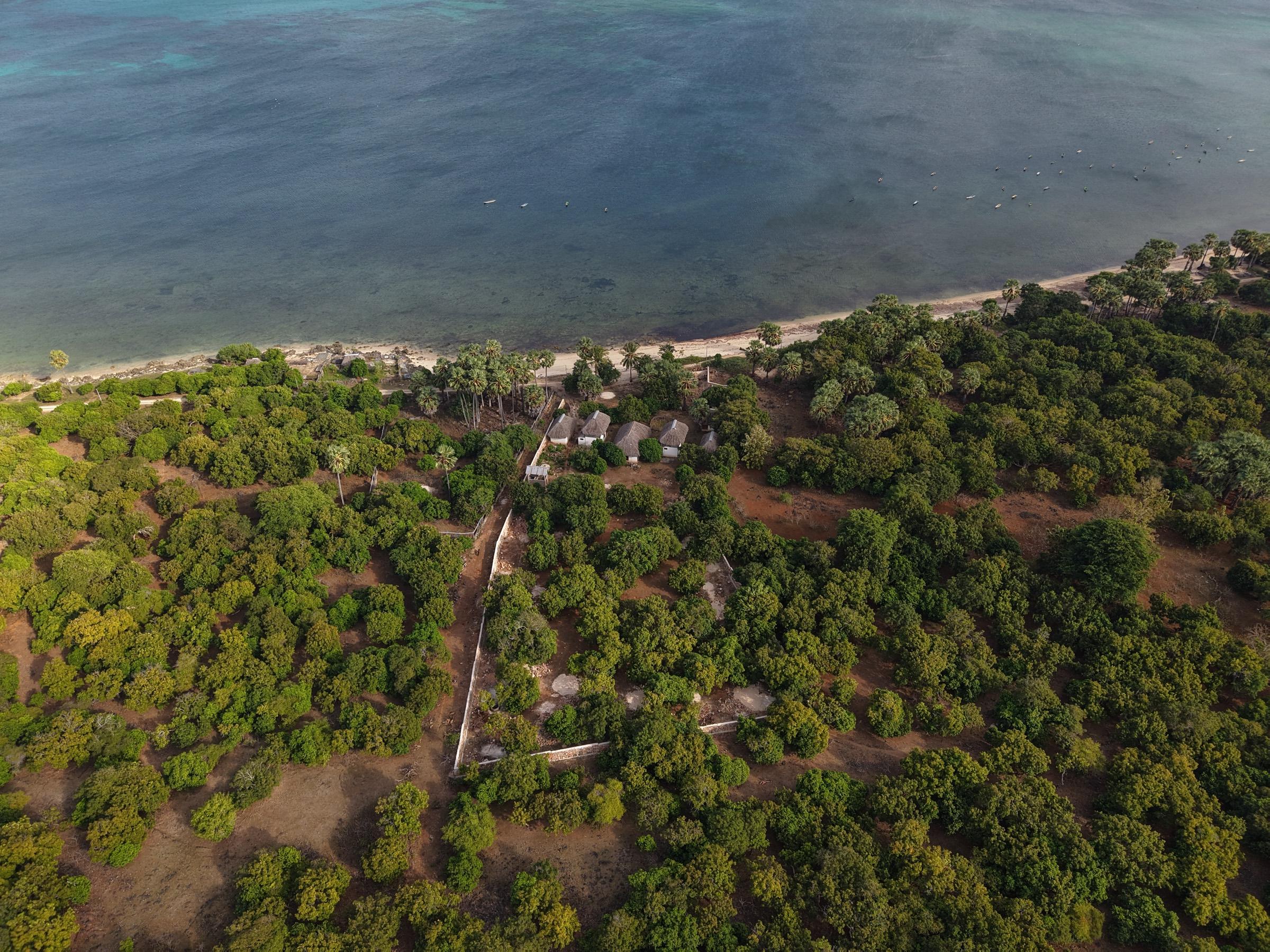 Aerial view of the turquoise reef flat and sandy beach in front of the plot